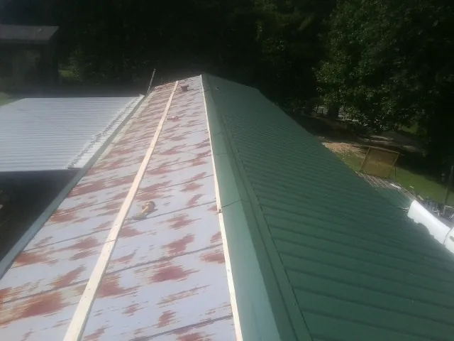 Old rusted panels beside newly installed green metal roofing — Wind Damage Roof Repair by Roofing Brothers in Craig
