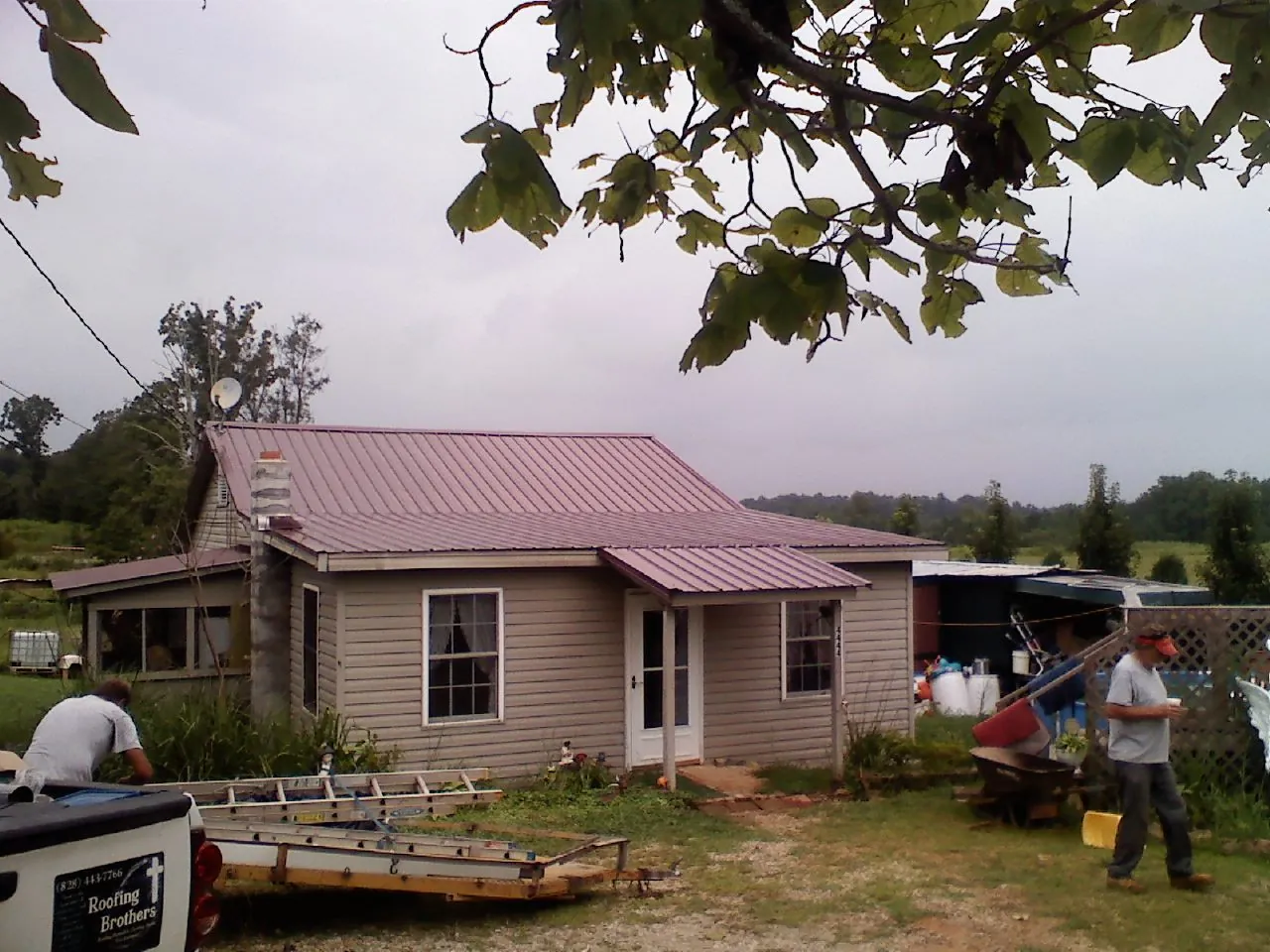 Crew finishing a mauve metal roof on a small farmhouse in Craig